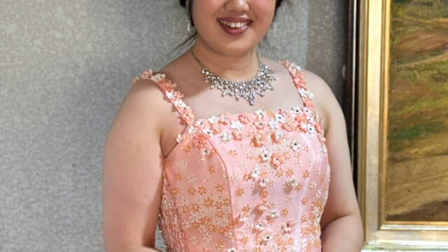 ピンク色のドレスを着て微笑む声楽家の若い女性