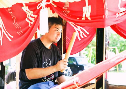 鯨船に乗り、座って太鼓を叩く青年