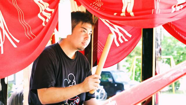 鯨船に乗り、座って太鼓を叩く青年