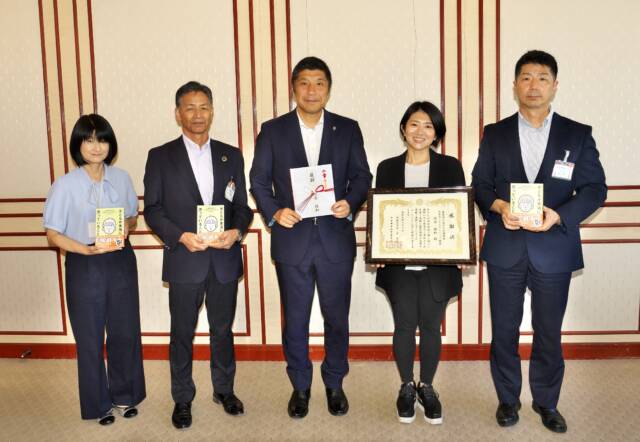 5人の人が並んで立っている。右から書籍を持った関係者、感謝状を持った精神科医さわさん、目録を持った森市長、書籍を持った関係者2人。