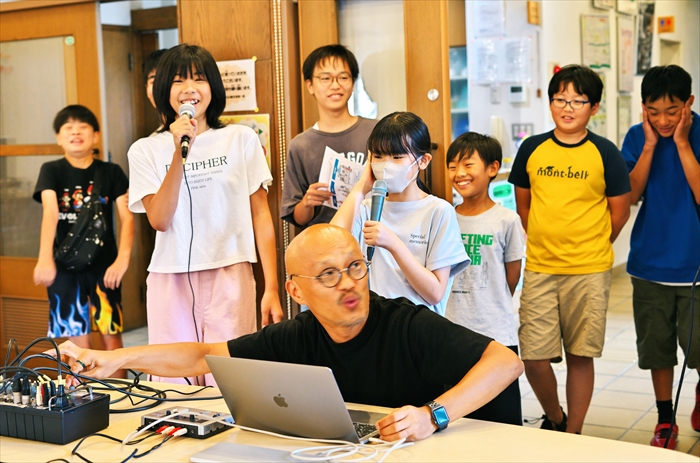 すわ公園交流館ホールで「こども四日市」ドキュメンタリー映画の主題歌レコーディングに臨む子どもたちと機材を操作する小林渚さん