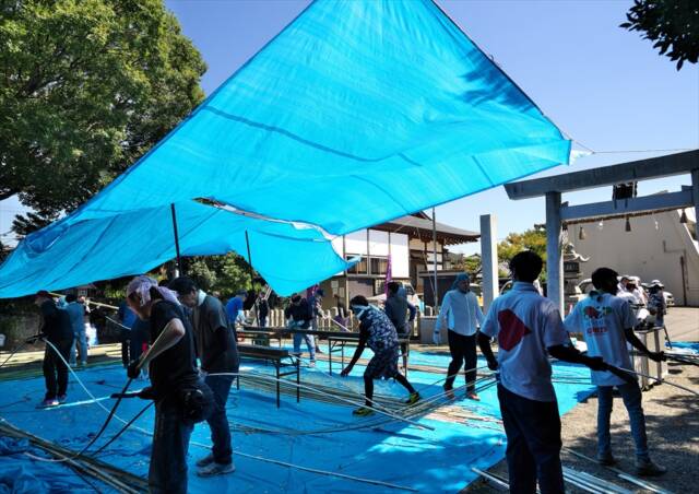 神社境内に広げたブルーシートの上で作業をする人々