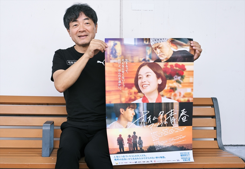 新作映画「オオムタアツシの青春」のポスターを手に持つ、四日市市出身の映画監督・瀬木直貴さん