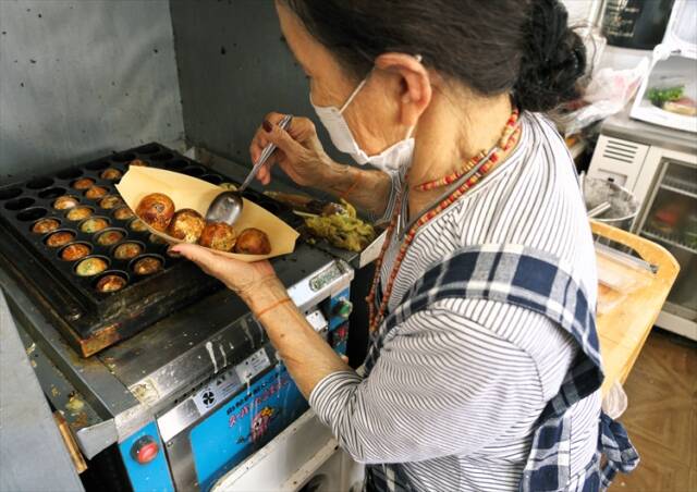 自動たこ焼き機で焼き上げた「踊るたこ焼き」を皿に盛り付ける服部さん