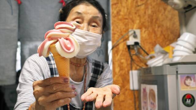 芸術的なソフトクリームを手にする看板娘の服部さん（84歳）＝四日市市塩浜