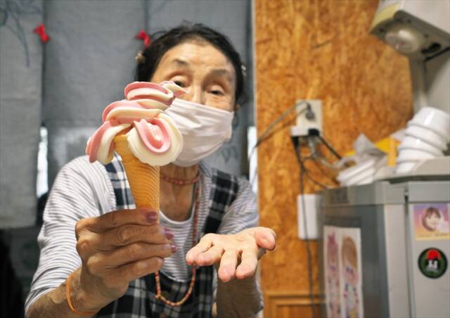 芸術的なソフトクリームを手にする看板娘の服部さん(84歳)=四日市市塩浜
