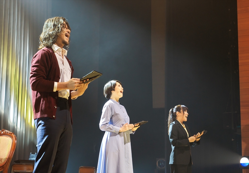 四日市市文化会館で上演されたリーディングミュージカル「Play a Life」の舞台。俳優3人がタブレットを手に歌唱している。