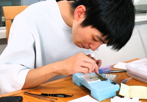 展足板の上で昆虫の羽や脚の位置をピンセットで整え、真剣な表情で標本を制作する椎名奏衣さん