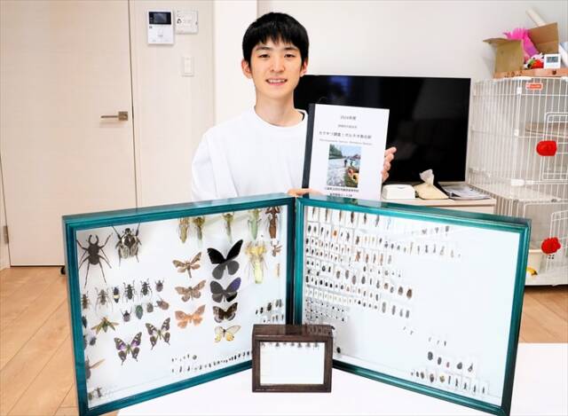 制作途中の昆虫標本の前で、高校時代の課題研究「日本とボルネオ島のカマキリ調査」の資料を手にする椎名奏衣さん