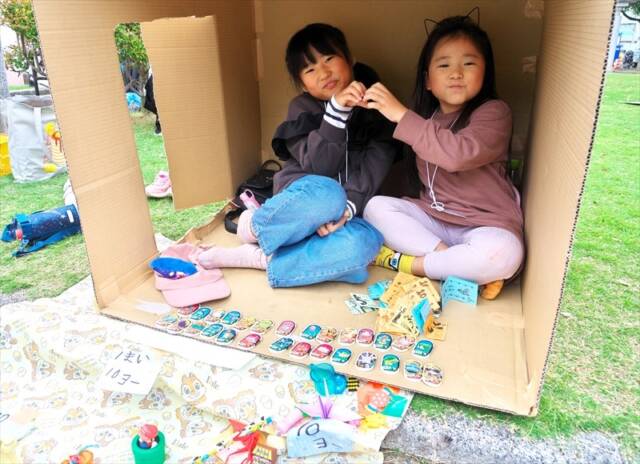 こども四日市2025で、自作の店舗で販売した売り上げを笑顔で見せる小学1年生の女の子2人