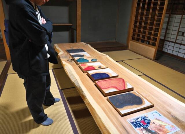 旧重盛邸「おやまの家」で展示された金沢健幸さんの浮世絵と制作工程を見つめる来場者。