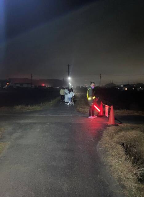 沿道で警備する人とその後ろに見物客