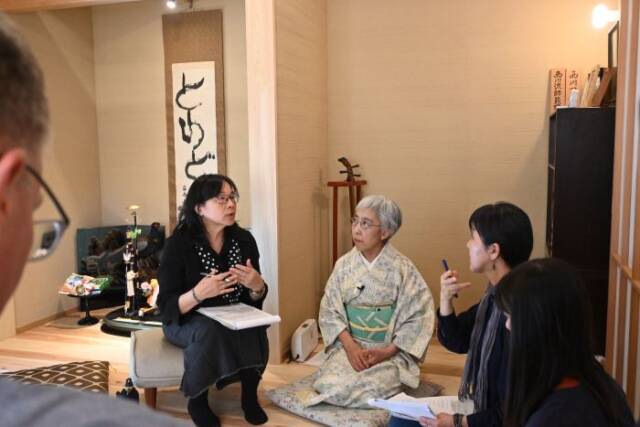 台湾の研究者が椅子に座り正座で話を聞く出口さんと通訳の女性