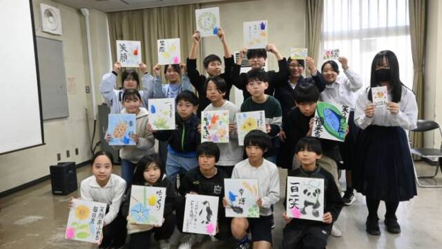 お年寄りへのメッセージを書いた色紙や年賀状を手にする小中学生