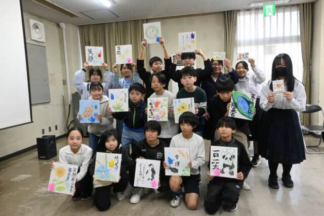 お年寄りへのメッセージを書いた色紙や年賀状を手にする小中学生