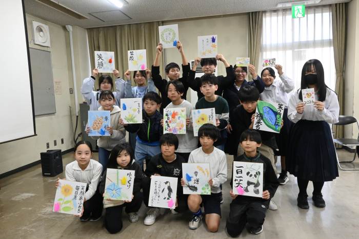 お年寄りへのメッセージを書いた色紙や年賀状を手にする小中学生