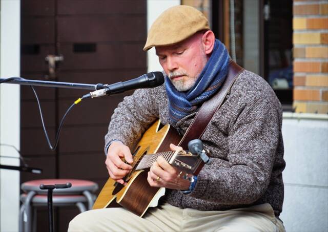 ギターを抱えて演奏するDanさん