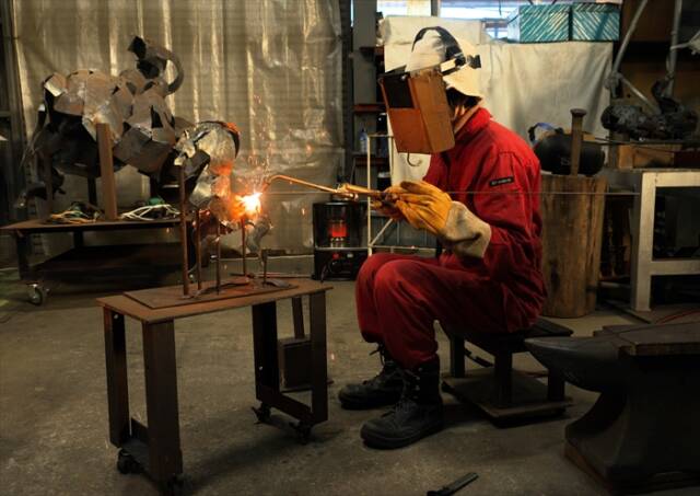 工房で溶断の火を使い、鉄材を加工する彫刻家・銅谷祐子さん