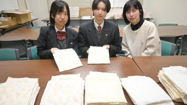 棺に入れる赤ちゃんの布団を置いて、手にも布団を持つ四日市農芸高校の生徒と、中村教諭（右）