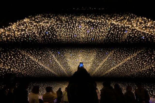 光のトンネルでスマホで写真を撮る人