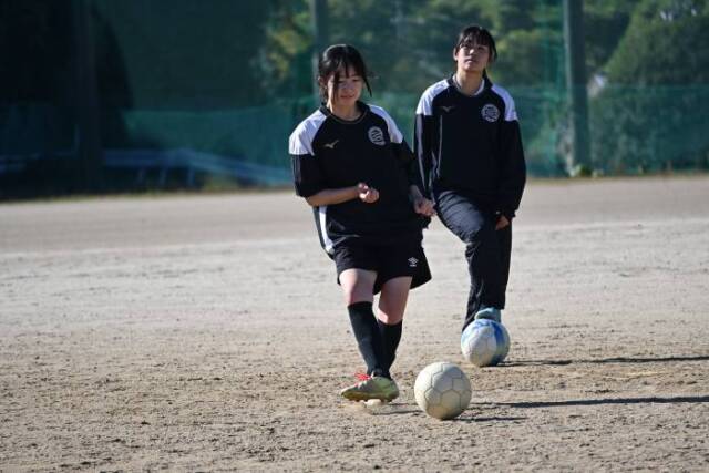 キックの練習をする部員。その後でボールに足をかけて順番を待つ部員がいる