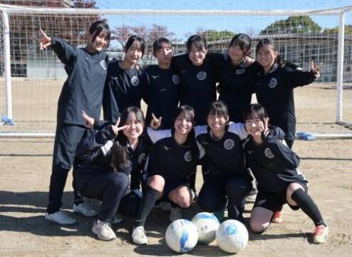 サッカーゴールの前で2列で肩を組む四日市南高校女子サッカー部員