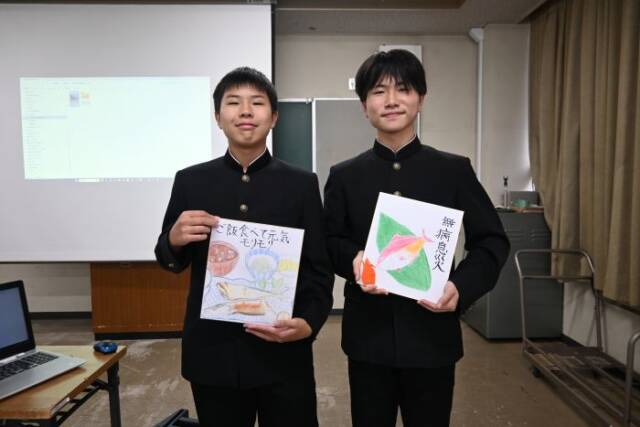 ご飯を食べて元気モリモリと書いた色紙と、無病息災と書いた色紙を手にする三滝中学校の男子生徒