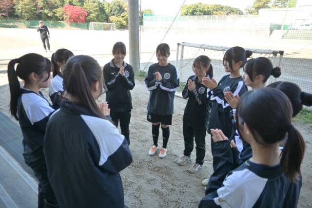 女子サッカー部員が円陣を組んで両手を合わせている