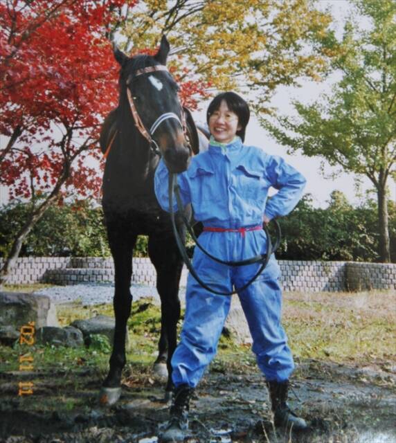 紅葉の中で馬のそばに立つ銅谷祐子さん。2002年11月、制作の合間に撮影