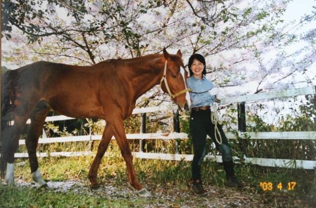 桜の季節に馬を散歩させる銅谷祐子さん。2003年4月撮影