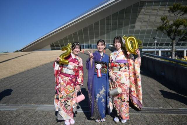 2と0のバルーンを手にする振袖の女性とピースサインをして立つ振袖の女性