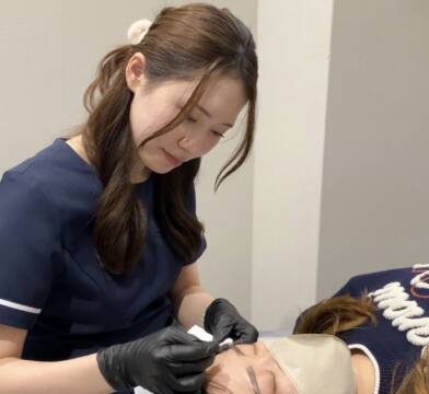 横になる人に眉のアートメイクを施す西田さん
