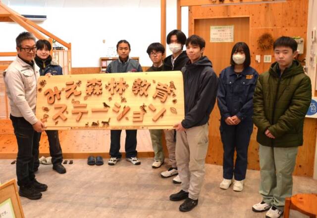 みえ森林教育ステーションと書かれた看板を持つ部員とステーションの担当者