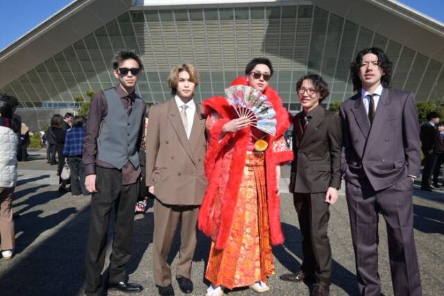 真ん中に赤い羽織袴の男性が四日市と書いた扇子を持ちスーツ姿の男性4人が脇に立つ