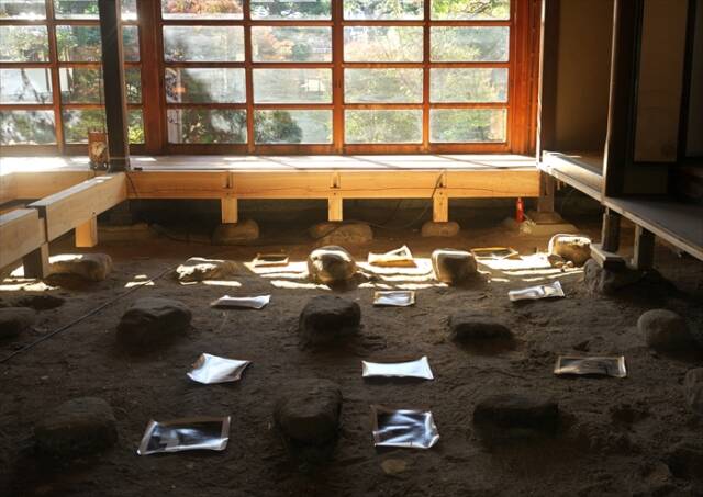 古民家の土間に額装せず並べられた、菰野町のお茶で染めた写真作品群