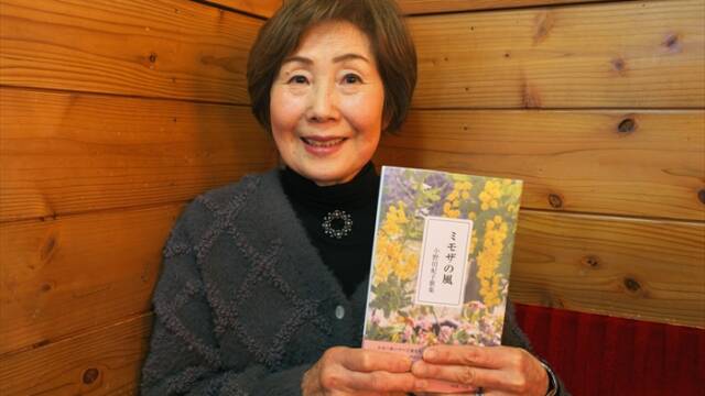 初歌集『ミモザの風』を手に持ち、ほほえむ小野田紀子さん