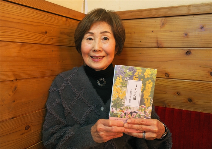 初歌集『ミモザの風』を手に持ち、ほほえむ小野田紀子さん