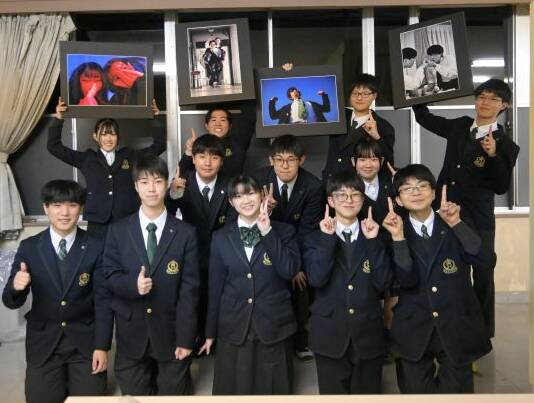 作品の写真パネルを手にする部員と笑顔で写真に納まる部員