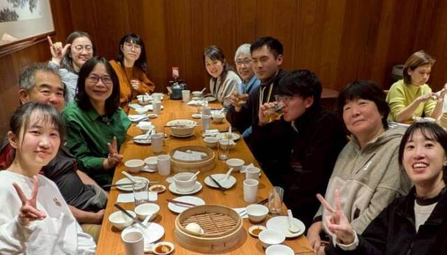 大勢の人が小籠包の店で笑顔で記念写真を撮る様子