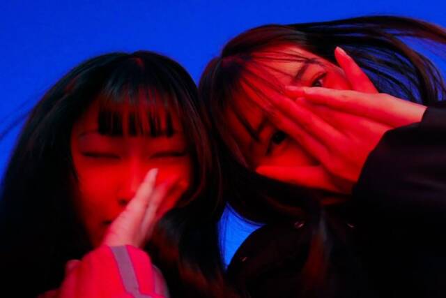 顔に手を当てる赤らんだ女子高生２人