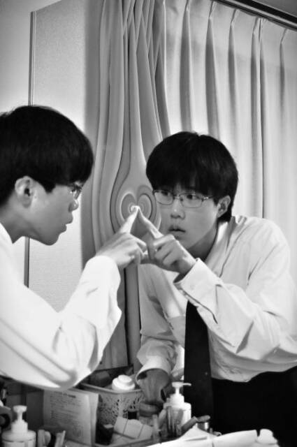 金属フィルムの鏡をのぞき込む男子高校生