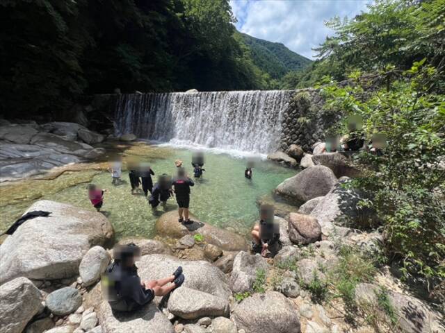 児童養護施設の子どもたちとロータリークラブ会員が川で遊ぶ様子、夏の自然体験活動の一場面