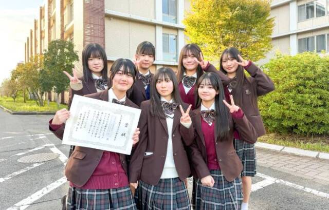 アイデアコンテスト2位の賞状を手に記念撮影するちゃいろがーるずの7人