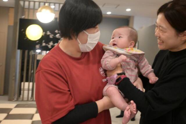 お母さんから大川さんに赤ちゃんを預けている