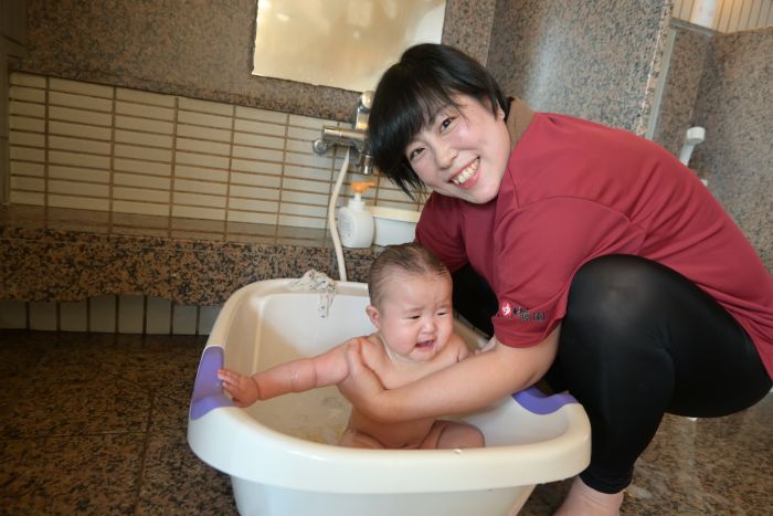 温泉でベビーバスを使って赤ちゃんをお風呂に入れる大川さん