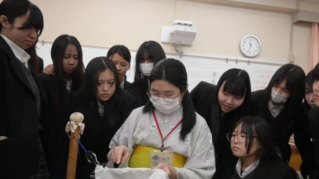 諸岡さんの説明を興味深く聞く生徒が諸岡さんの後ろからのぞき込む様子