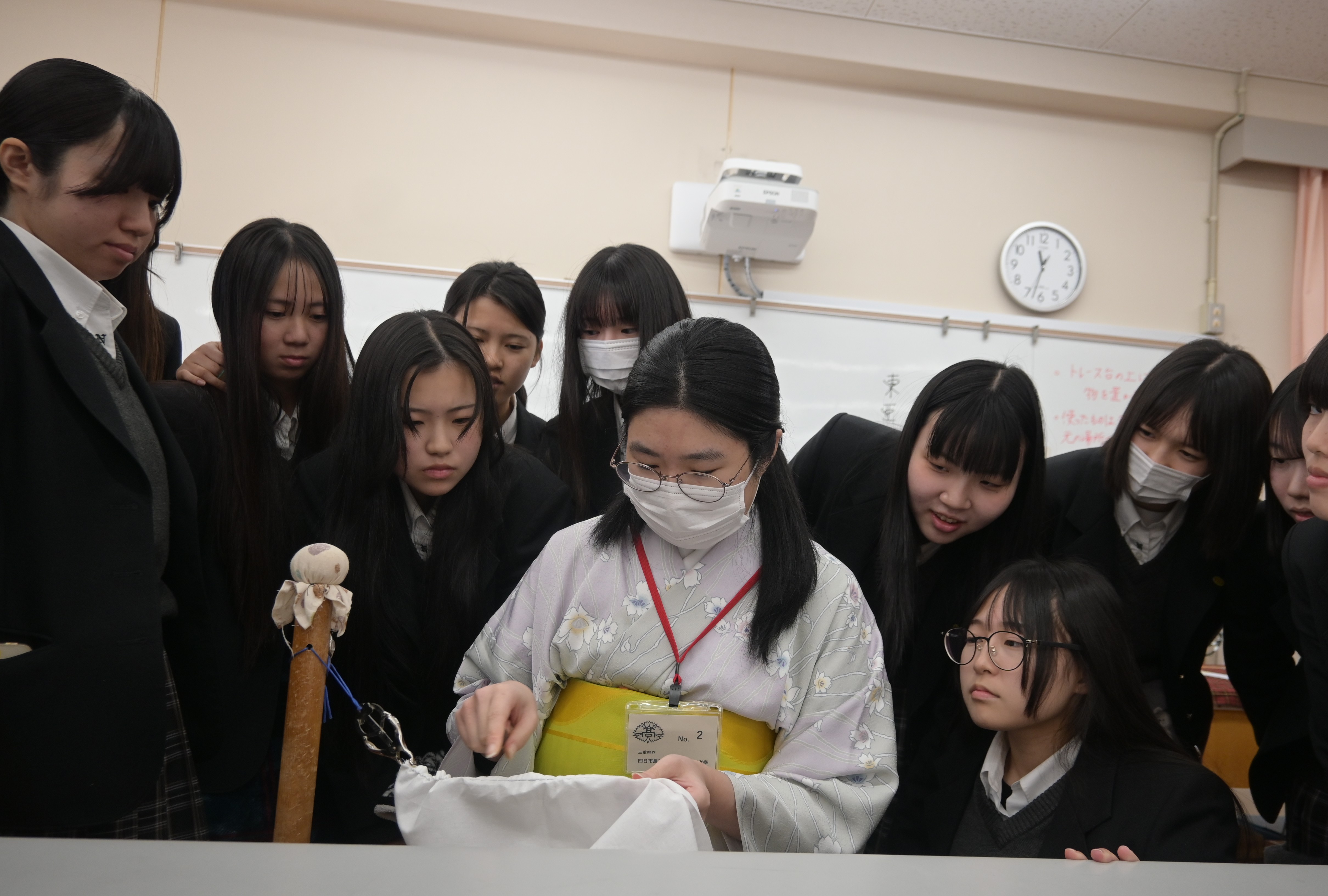 諸岡さんの説明を興味深く聞く生徒が諸岡さんの後ろからのぞき込む様子