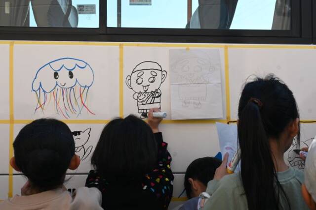 マスキングテープで仕切られたスペースにこにゅうどうくんの絵を描く子