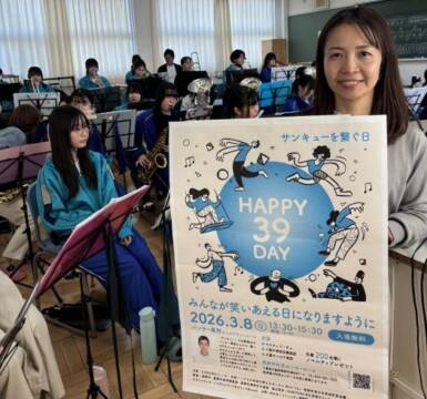 HAPPY39DAYのポスターを手に八風中学校吹奏楽部の部員の横に立つ伊藤さん