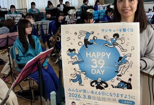 HAPPY39DAYのポスターを手に八風中学校吹奏楽部の部員の横に立つ伊藤さん